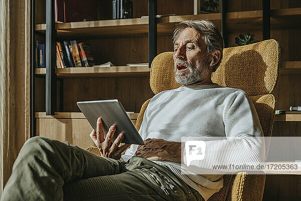 Mann spricht über Videokonferenz durch digitale Tablette  während er zu Hause sitzt