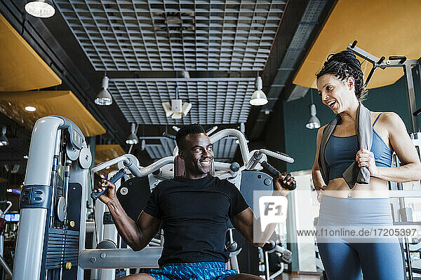 Male and female sports people smiling while looking at each other in health club