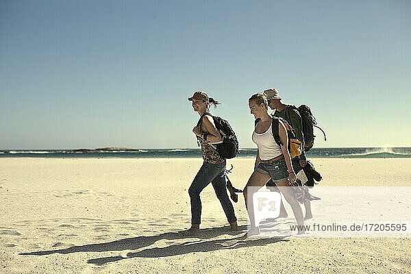 Männlicher und weiblicher Tourist spazieren auf Sand gegen den Himmel an einem sonnigen Tag am Wochenende