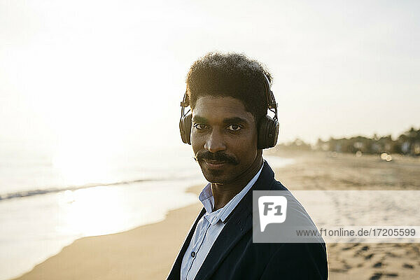 Afro man with headphones at beach during sunny day