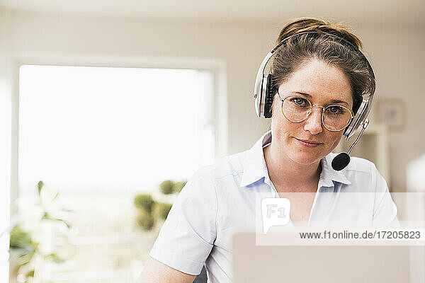 Businesswoman in eyeglasses wearing wireless headphones