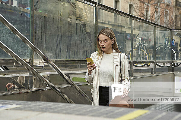 Schöne Frau  die ein Mobiltelefon benutzt  während sie von einer U-Bahn-Station aufsteigt