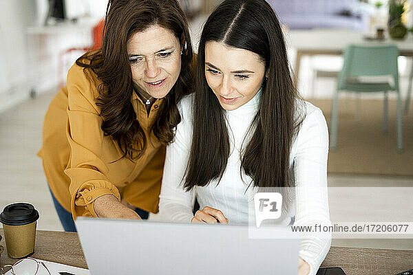 Mutter  die ihrer Tochter beim Lernen am Laptop zu Hause hilft