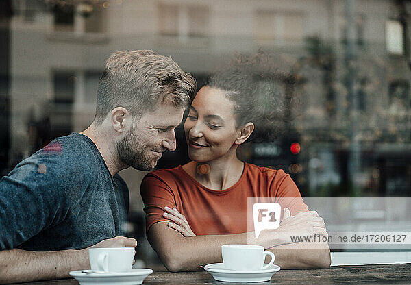 Paar sitzt lächelnd am Fenster eines Cafés