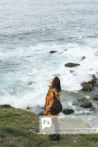 Junge Frau steht auf einem Felsen am Meer