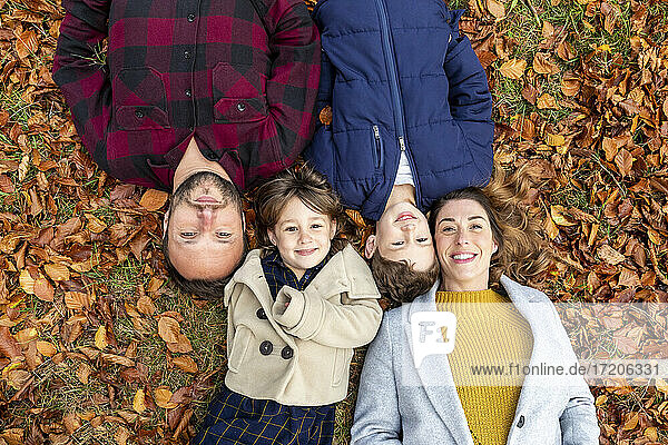 Lächelnde Familie auf einem gefallenen Blatt im Wald im Herbst liegend
