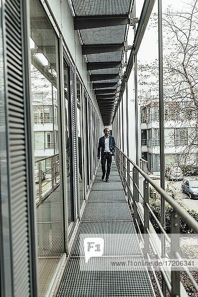 Geschäftsmann schaut weg  während er auf dem Balkon eines Büros spazieren geht