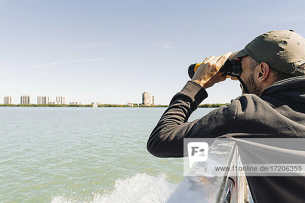 USA  Florida  Sanibel  Mann betrachtet das Meer durch ein Fernglas