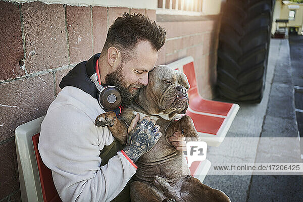 Männlicher Fitnesstrainer umarmt Bulldogge vor dem Fitnessstudio