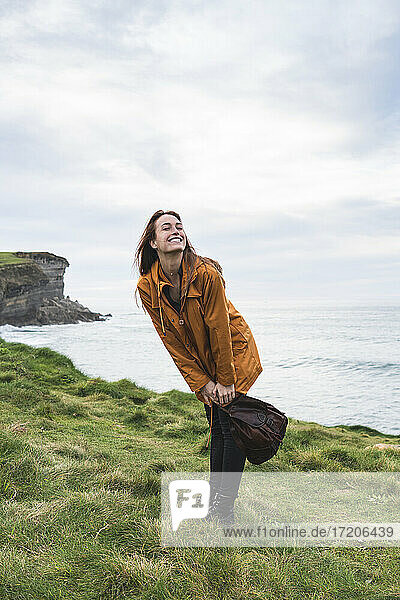 Happy woman standing on grass by sea