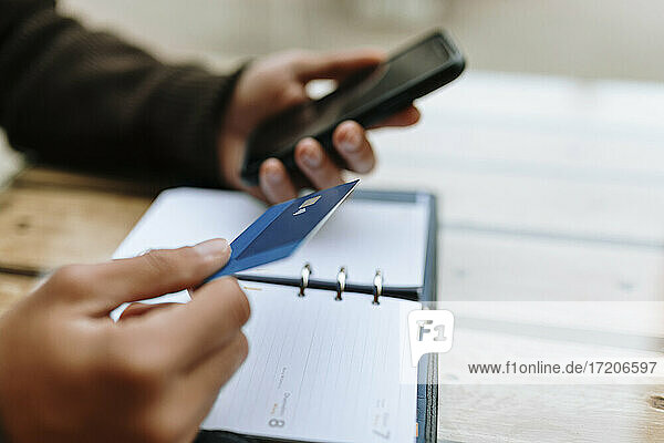 Junger Mann bei einer Online-Zahlung mit Kreditkarte über ein Smartphone