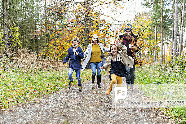 Glückliche Familie beim gemeinsamen Laufen auf einem Waldweg