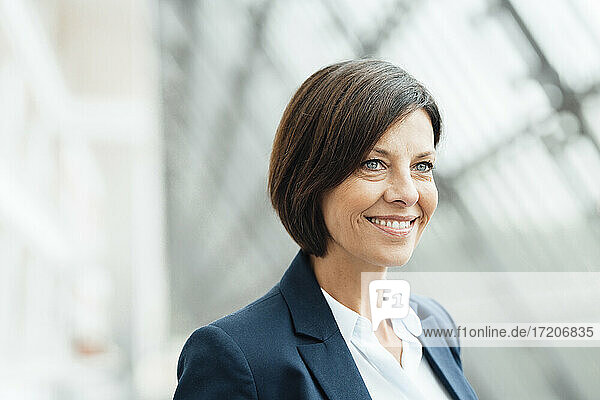 Lächelnde Geschäftsfrau  die im Büro wegschaut