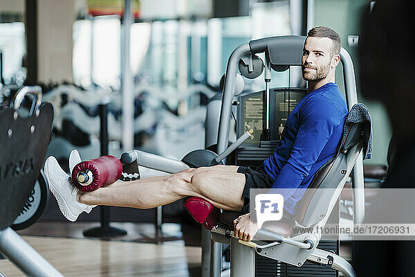 Handsome sportsman exercising on weightlifting machine in gym
