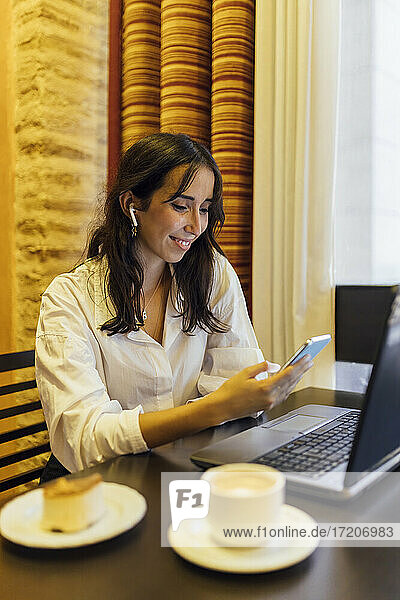 Unternehmerin  die im Café sitzend ein Smartphone benutzt