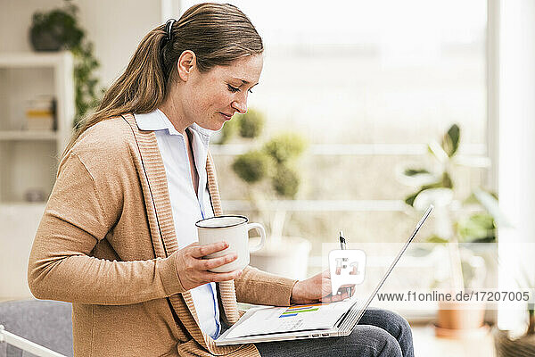 Geschäftsfrau schreibt auf einem Dokument und hält eine Kaffeetasse