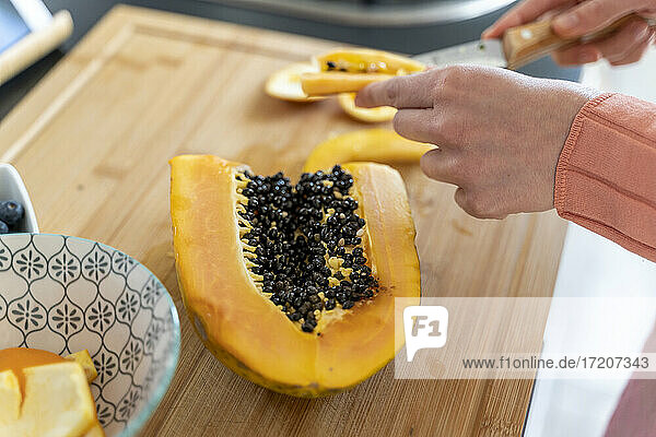 Frau schneidet Papaya in der Küche zu Hause