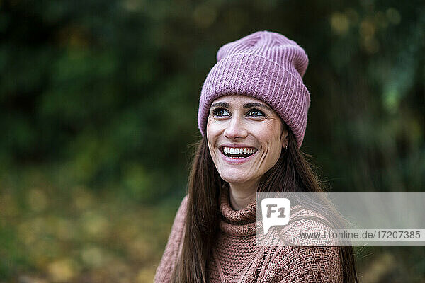 Porträt einer schönen Frau mit rosa Strickmütze  die im Freien steht und lächelt