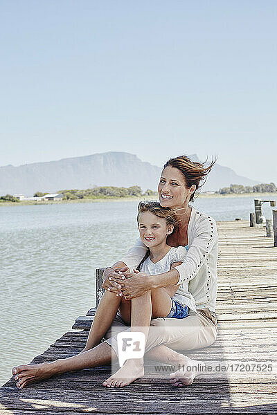 Lächelnder Junge mit Mutter auf dem Pier sitzend