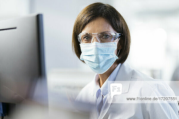 Technikerin mit Schutzbrille im Labor während einer Pandemie
