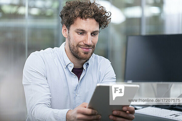Junger männlicher Unternehmer  der ein digitales Tablet im Büro benutzt