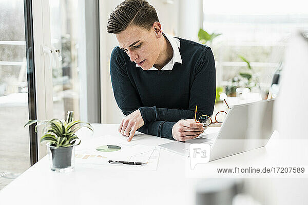 Konzentrierter männlicher Berufstätiger  der ein Dokument liest  während er im Büro zu Hause sitzt