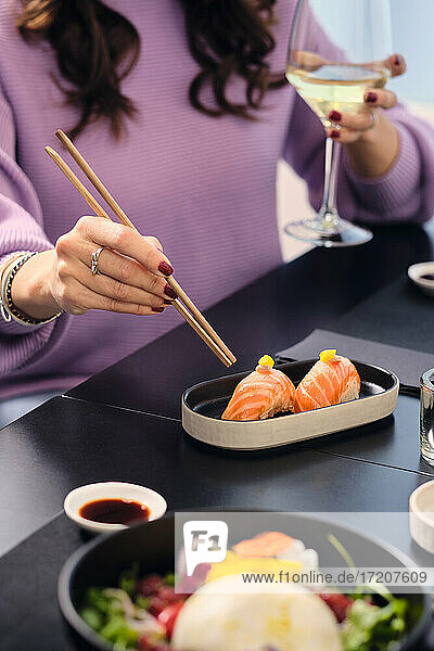 Ältere Frau isst Sushi mit Stäbchen im Restaurant
