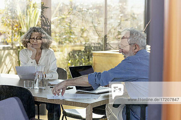 Senior couple working while sitting by table at home