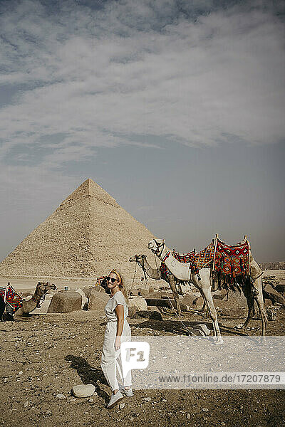 Weiblicher Tourist schaut über die Schulter in die Kamera vor der Großen Pyramide von Gizeh