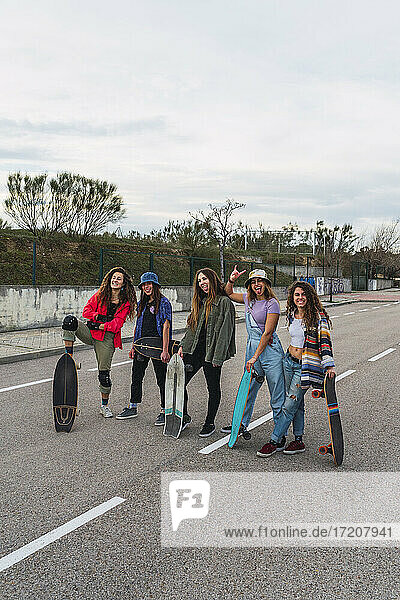 Glückliche Freundinnen mit Skateboards auf der Straße stehend