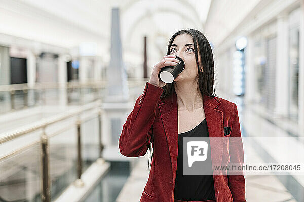 Geschäftsfrau blickt auf  während sie in der U-Bahn-Station einen Kaffee trinkt