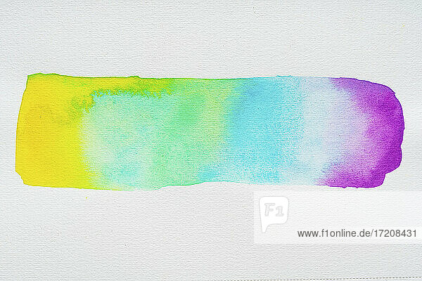 Rainbow watercolor paint gradient brush stroke on white paper