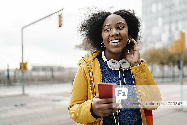Happy woman looking away with smart phone