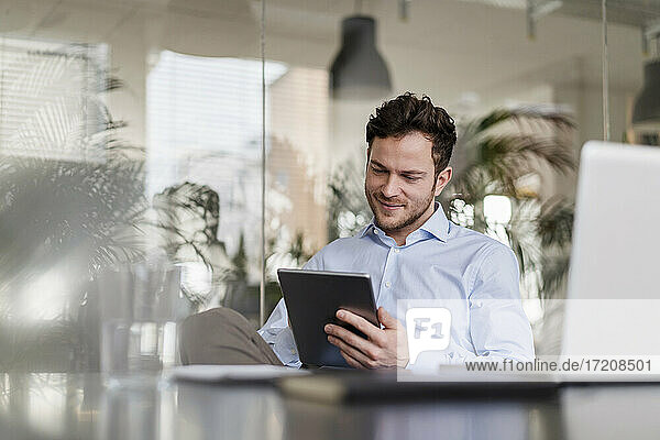 Smiling businessman using digital tablet at office