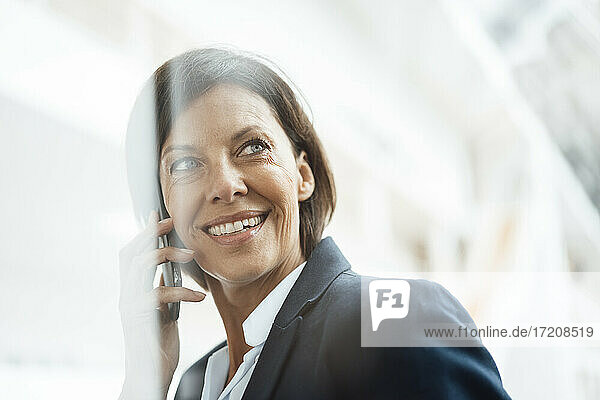 Lächelnde Geschäftsfrau  die im Büro mit einem Mobiltelefon spricht