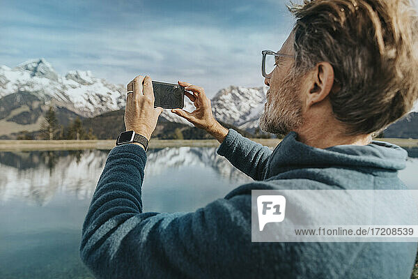Älterer Mann fotografiert die Aussicht  während er am See steht  Hochkonig  Salzburger Land  Österreich