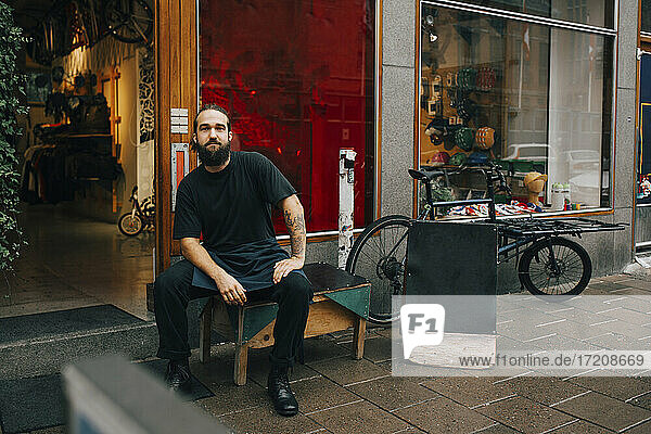 Male mechanic sitting on table outside retail store