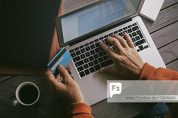 Senior Mann die Hände tun Online-Zahlung mit Kreditkarte durch Laptop zu Hause