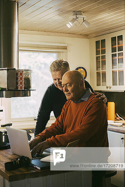 Homosexual couple using laptop in kitchen at home