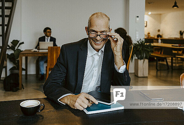 Porträt eines lächelnden männlichen Unternehmers mit Augen am Konferenztisch im Off