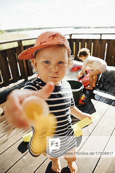 Porträt von niedlichen Jungen geben Spielzeug im Stehen im Freien während des sonnigen Tages