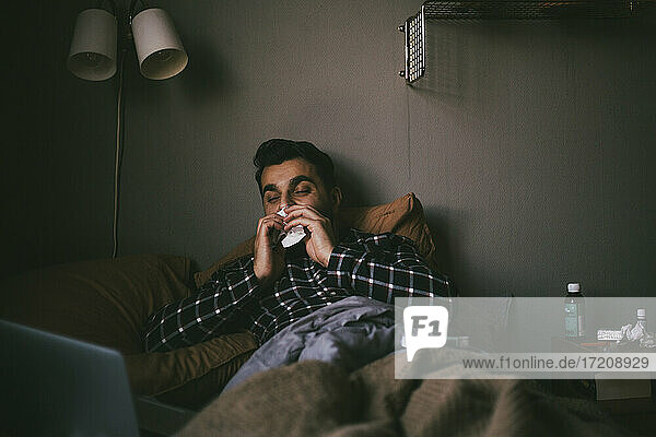 Man blowing nose while having online consultation at home