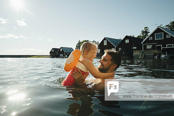 Seitenansicht der fröhlichen Tochter mit Vater im See während der Ferien
