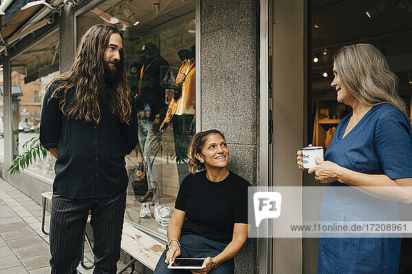Male entrepreneur discussing with female colleagues outside clothes store