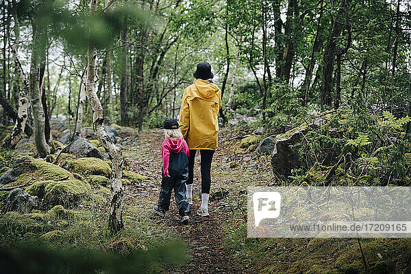 Rear view of mother and daughter walking in forest
