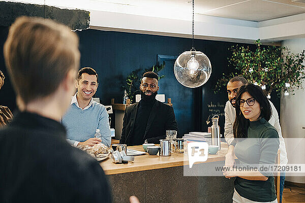 Lächelnde männliche und weibliche Kollegen  die am Tisch in einem kreativen Büro diskutieren