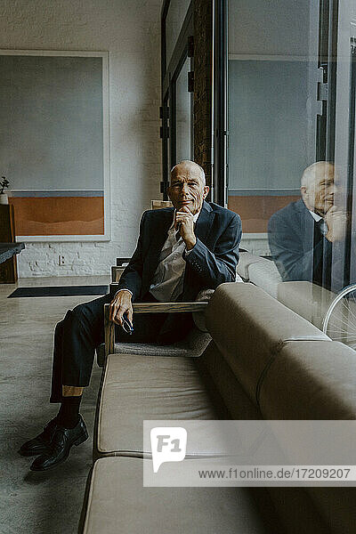 Porträt eines männlichen Unternehmers  der über einem Sofa im Büro sitzt