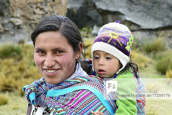 Smiling indigenous woman with falling asleep infant on her back  Junín province  Peru  South America