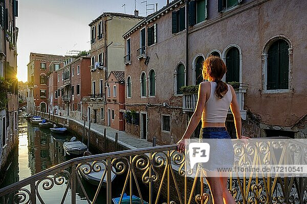 Junge Frau lehnt an einer Brücke am Rio Santa Catherina im Abendlicht  Cannaregio  Venedig  Venetien  Italien  Europa