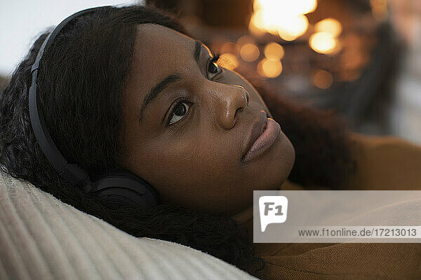 Close up serene woman listening to music by fireplace